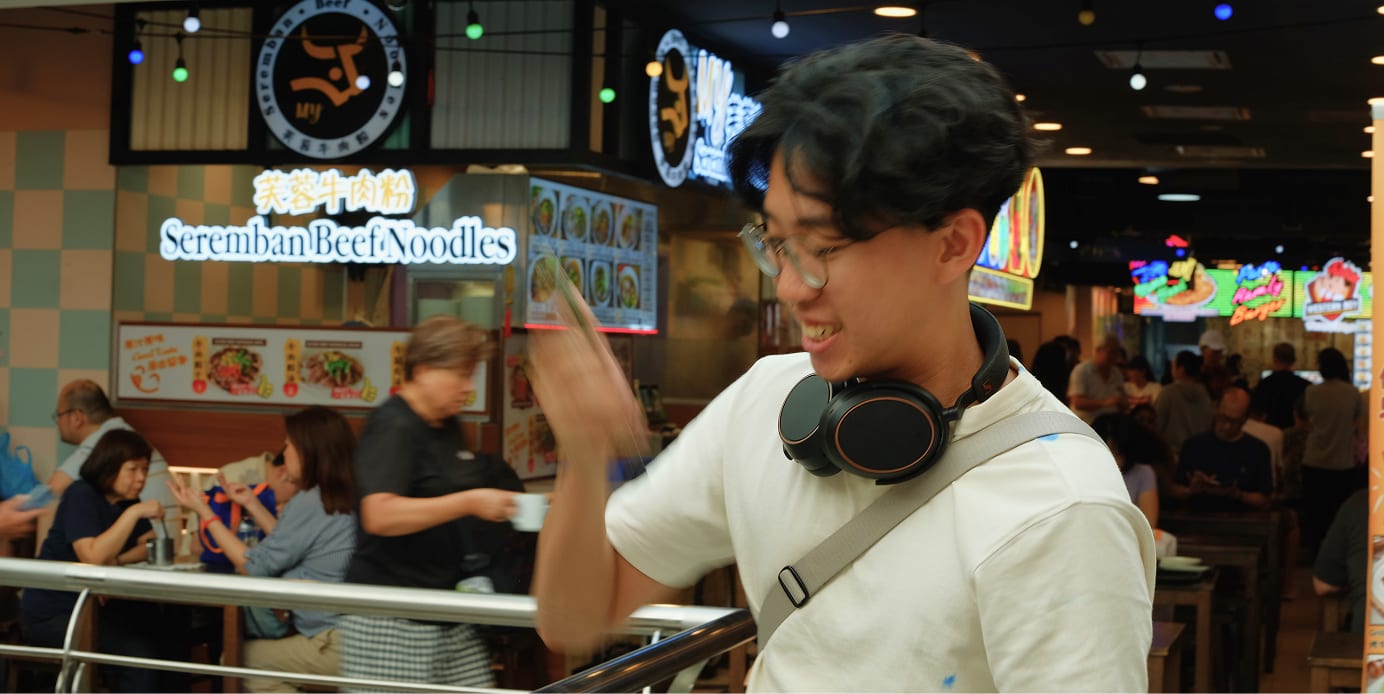 shaking the phone at a hawker centre, in front of a seremban beef noodles stall
